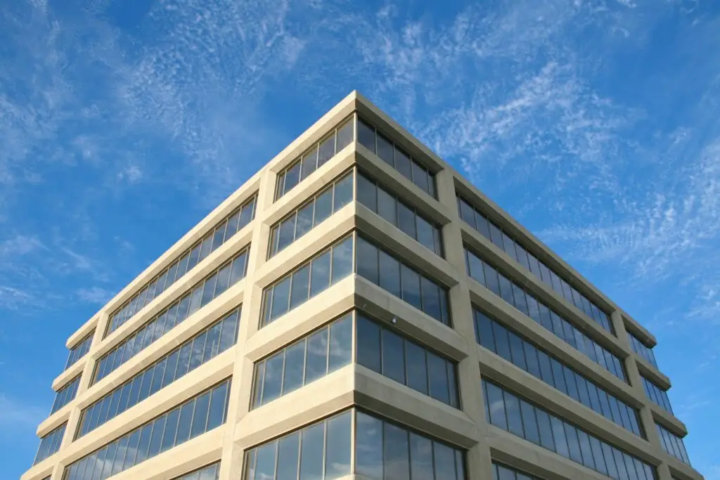 Corner view of a modern office building with reflective windows under a clear blue sky.